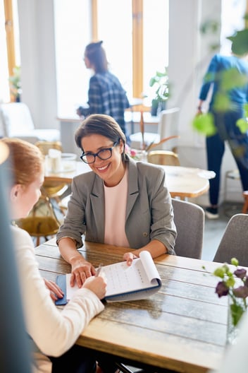 Woman assisting a woman with review of a resume.